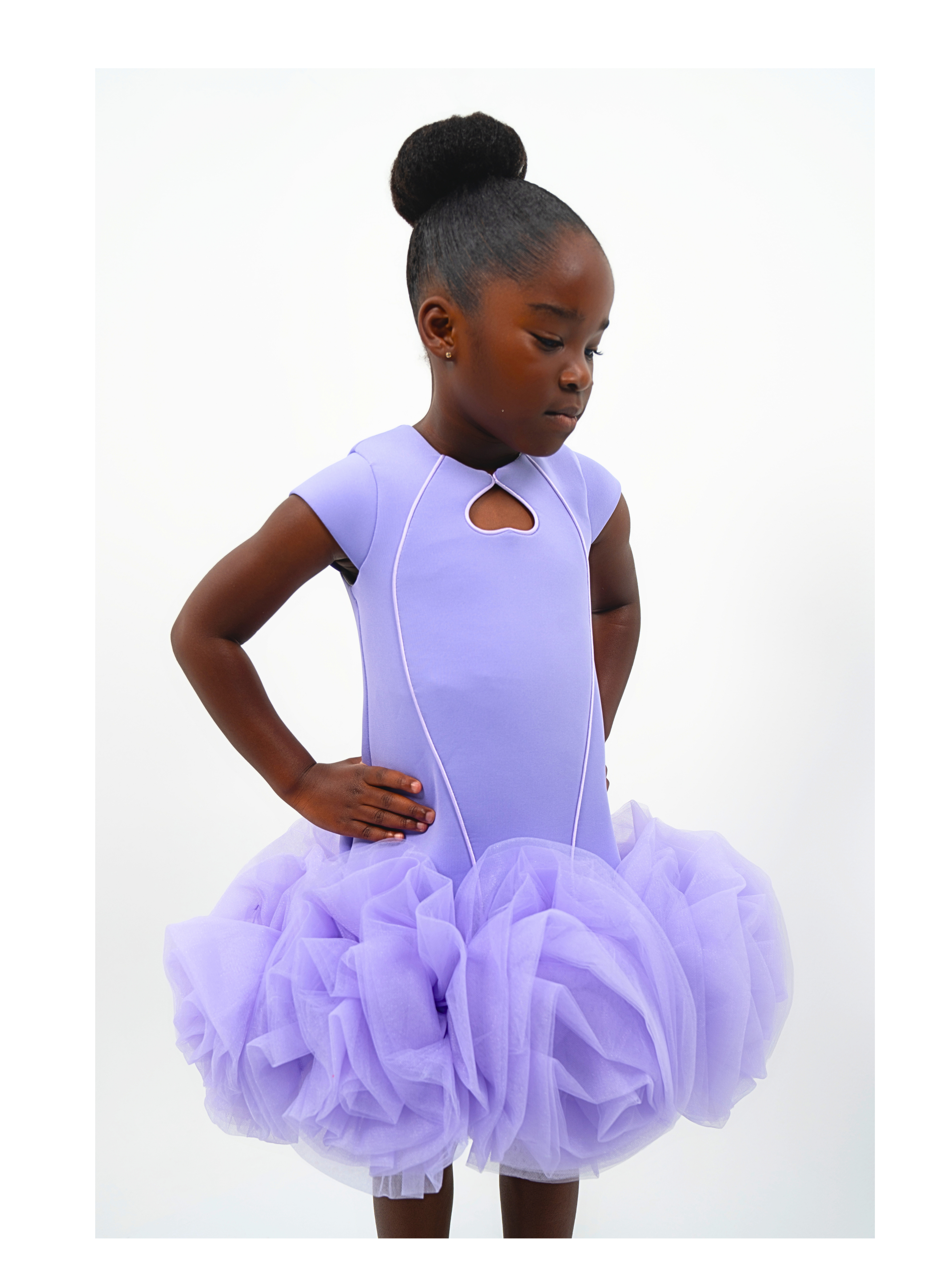 Girl wearing lavender puff-ball dress with tulle skirt and keyhole neckline, styled for birthday or photoshoot